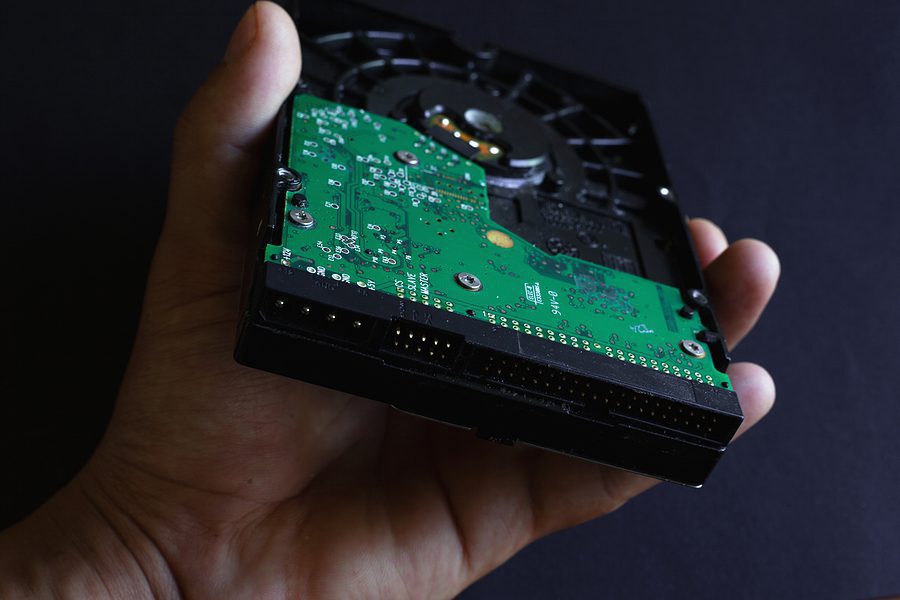 Close up of a hand holding an old hard drive.