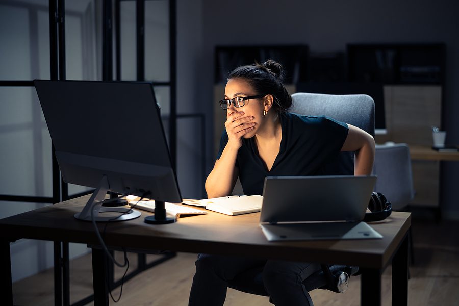 Business manager sitting a her desk working on her computer and realizes a data breach.