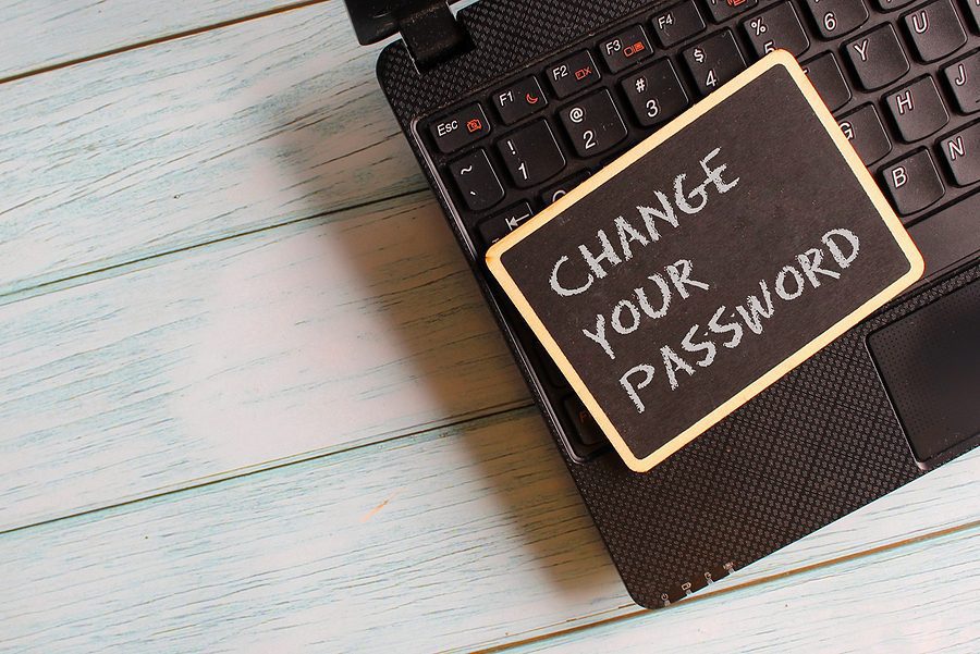 Technology concept. Mini blackboard with text CHANGE YOUR PASSWORD on laptop.
