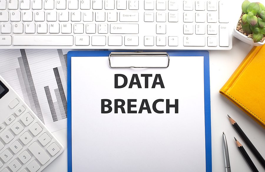 DATA BREACH written on paper with keyboard, chart, calculator and notebook