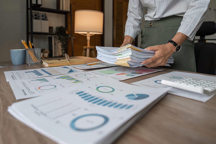 Business woman holding a stack of confidential business paperwork at her desk.