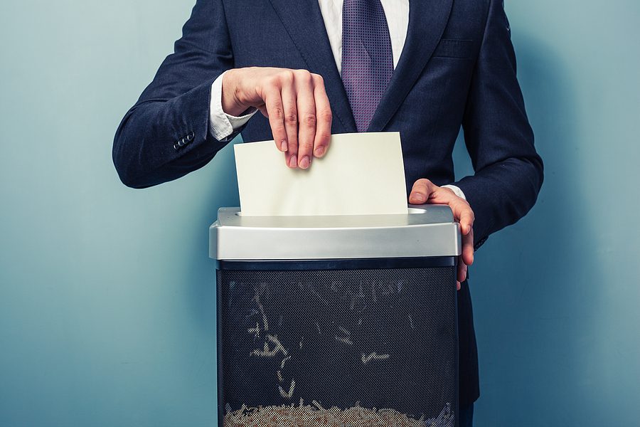 Businessman in suit shredding a paper document. 