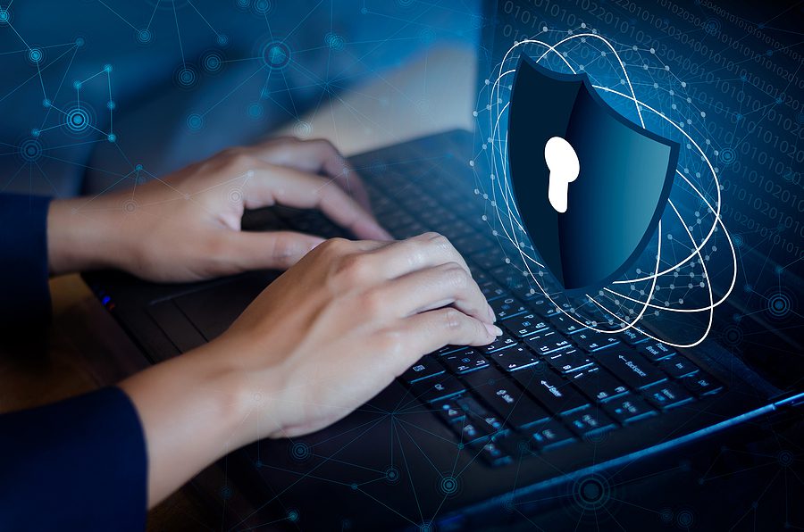 Close up of hands typing on a keyboard with a cyber lock shield on the screen. 