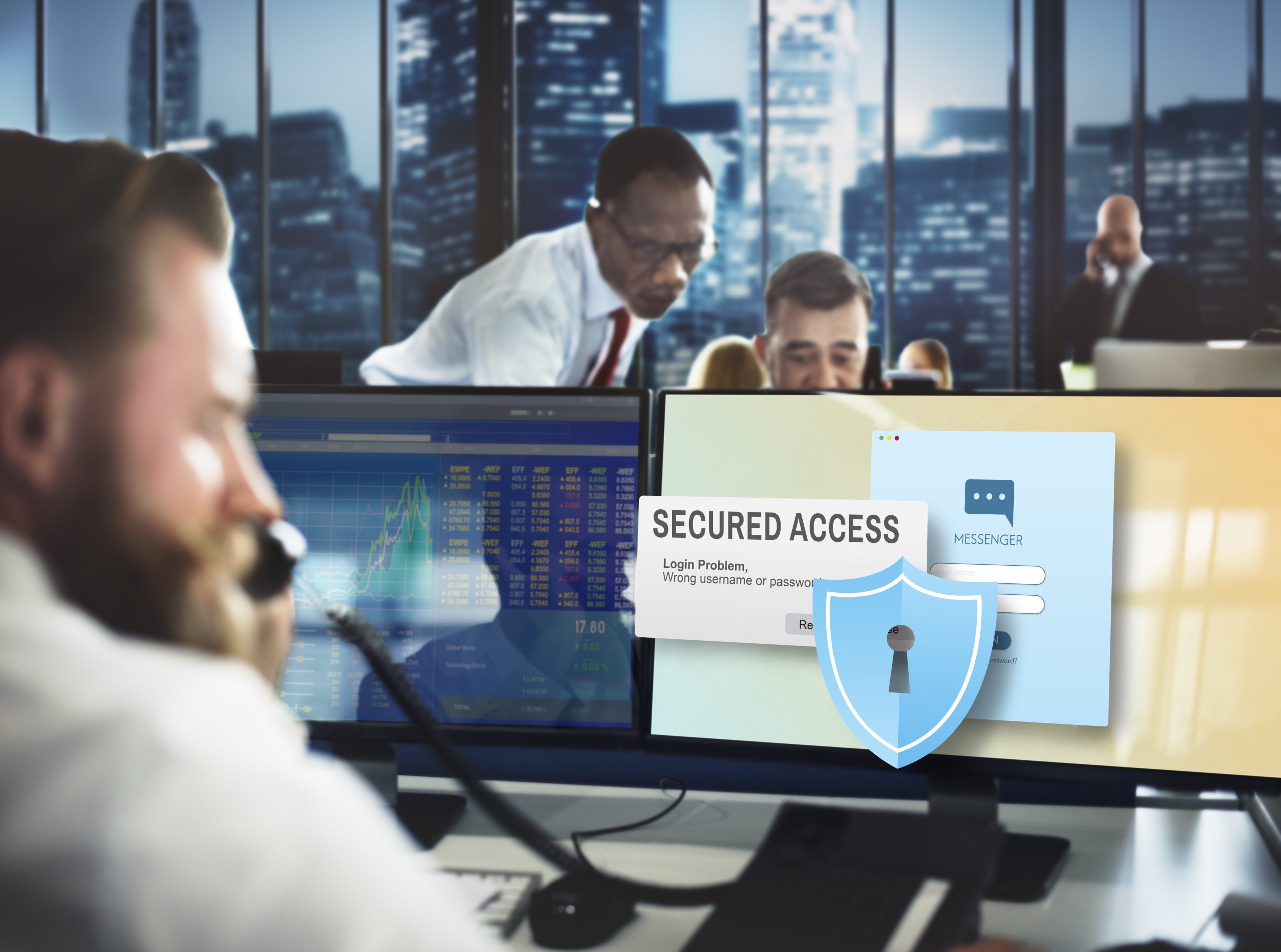 A male employee on the phone with a secured password protected screen on his computer. 