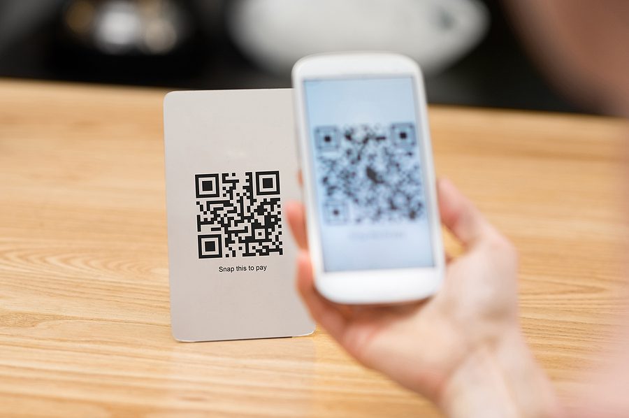 Closeup of a hand holding a phone and scanning a QR code. 