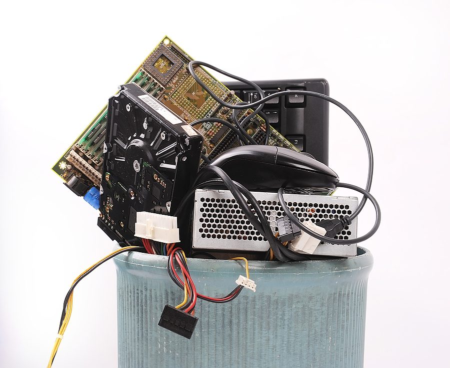 Pile of old computer parts sitting on top of a metal trash can. 