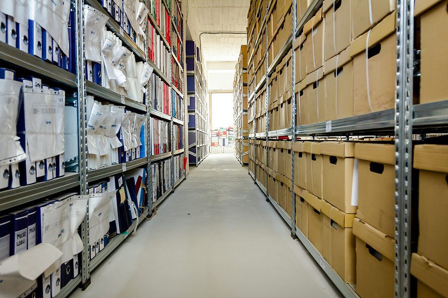 Stacks of files and boxes on shelves in a corporate storage room. 
