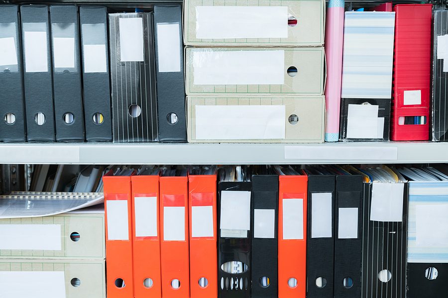 Colorful folders on a shelf, filled with old paper files. 